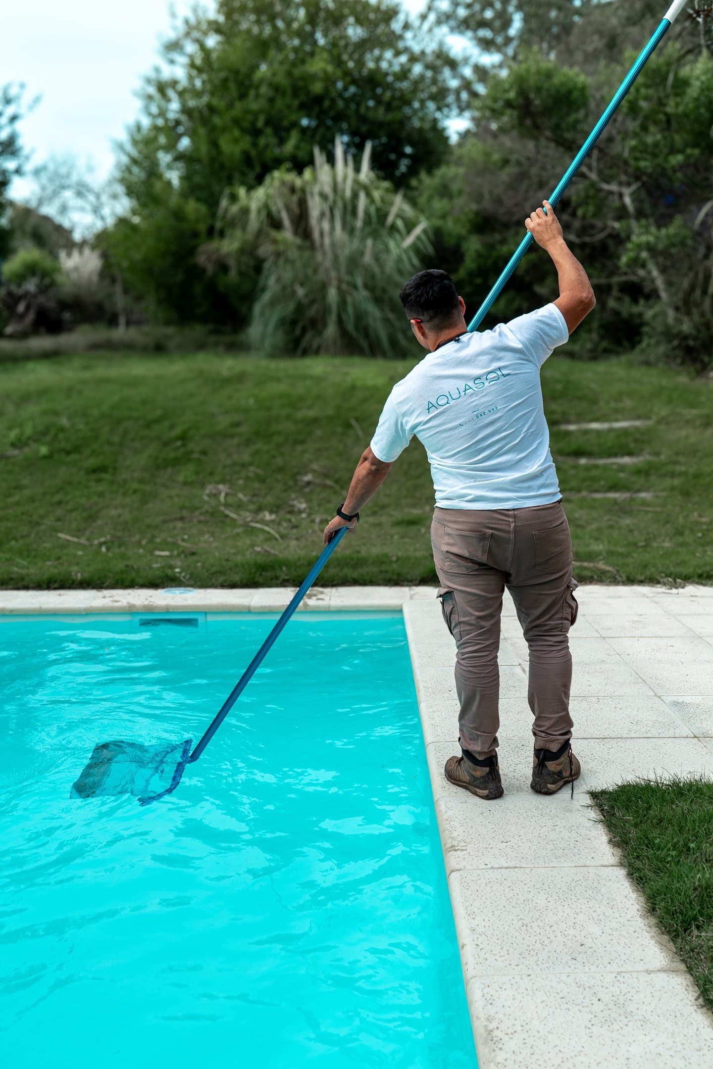 Técnico de Aquasol limpiando la superficie de una piscina con red