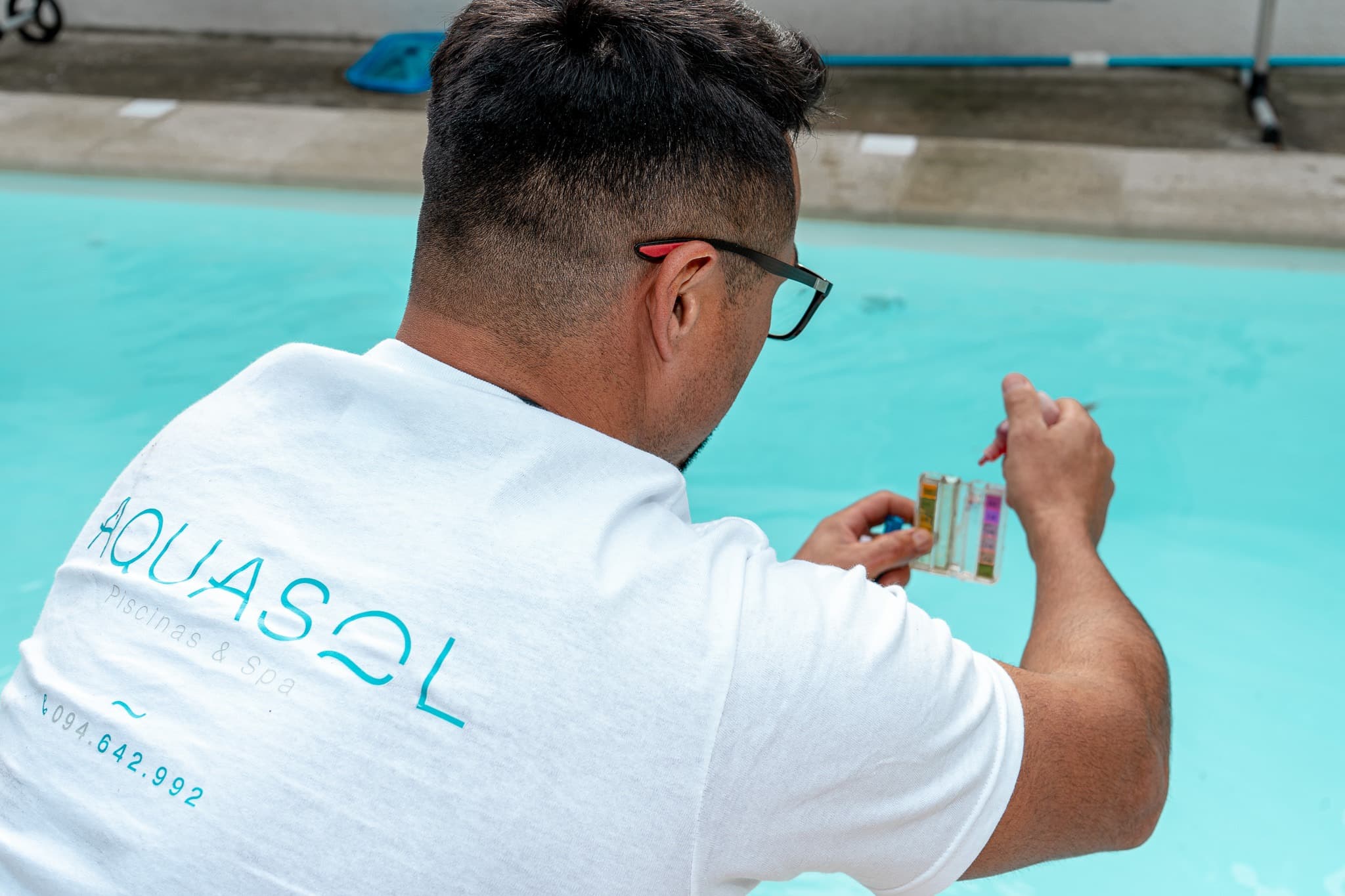 Técnico de Aquasol midiendo los parámetros del agua con un test kit al borde de la piscina